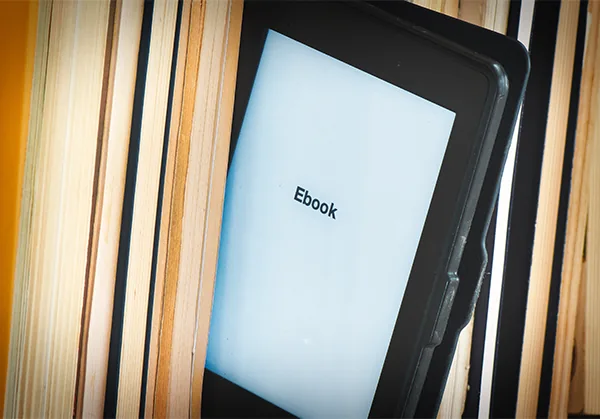 Basılı kitapların arasında duran bir e-kitap okuyucu